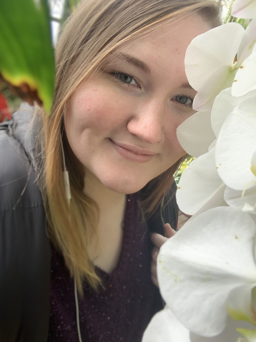 Young blonde female smiling among some flowers