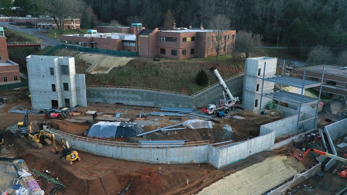 Aerial photograph of construction zone shows two concrete stairwell towers and the first few steel beams.