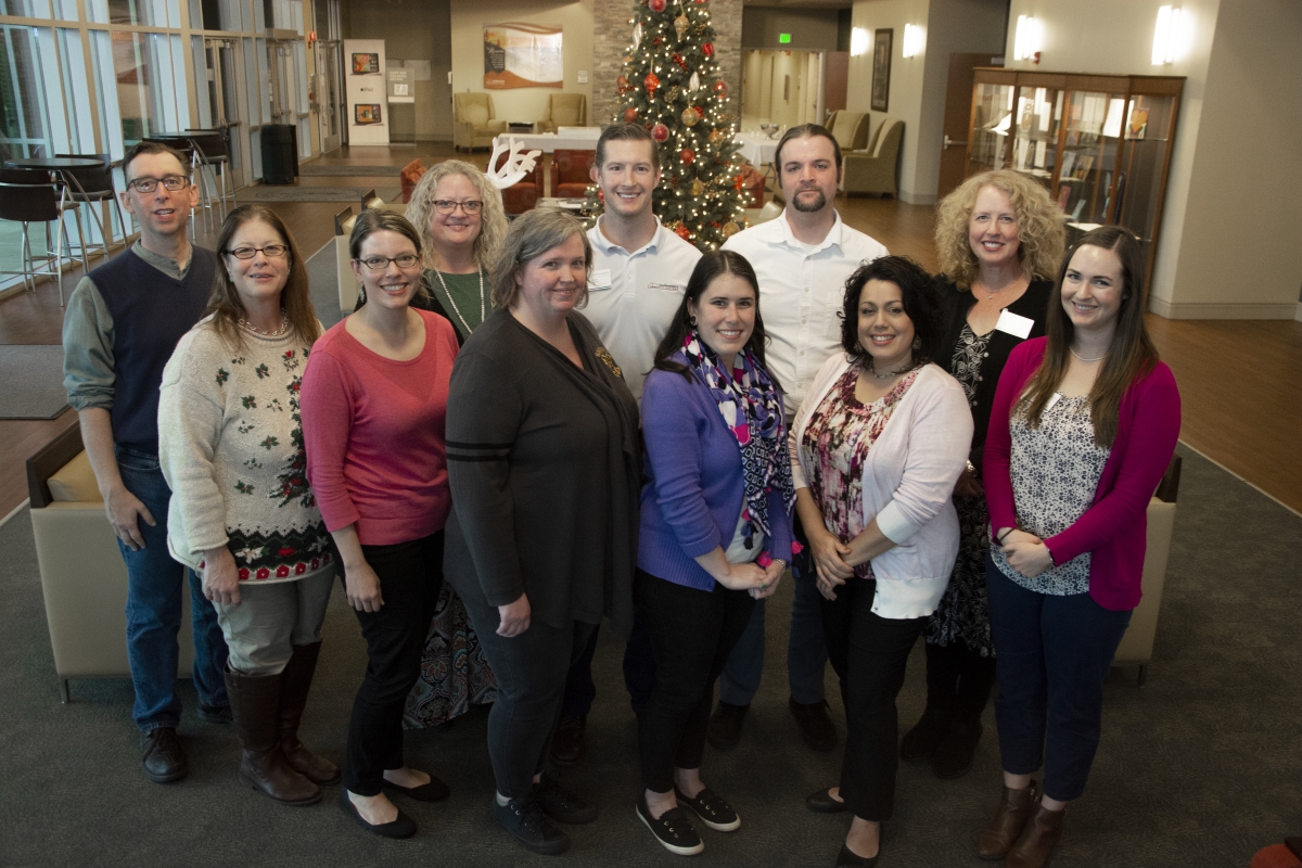 Eleven SCC employees pose with Christmas tree in background.