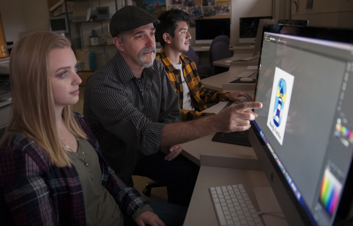 Instructor works with two students at computer monitors