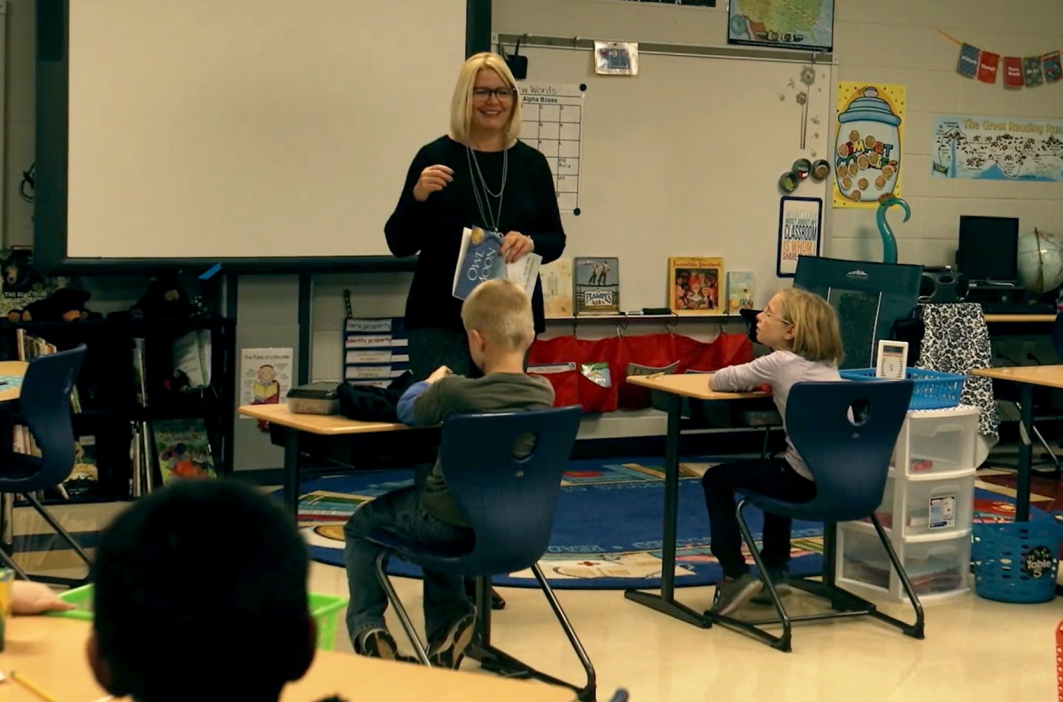 Teacher speaks to elementary students in a classroom setting.