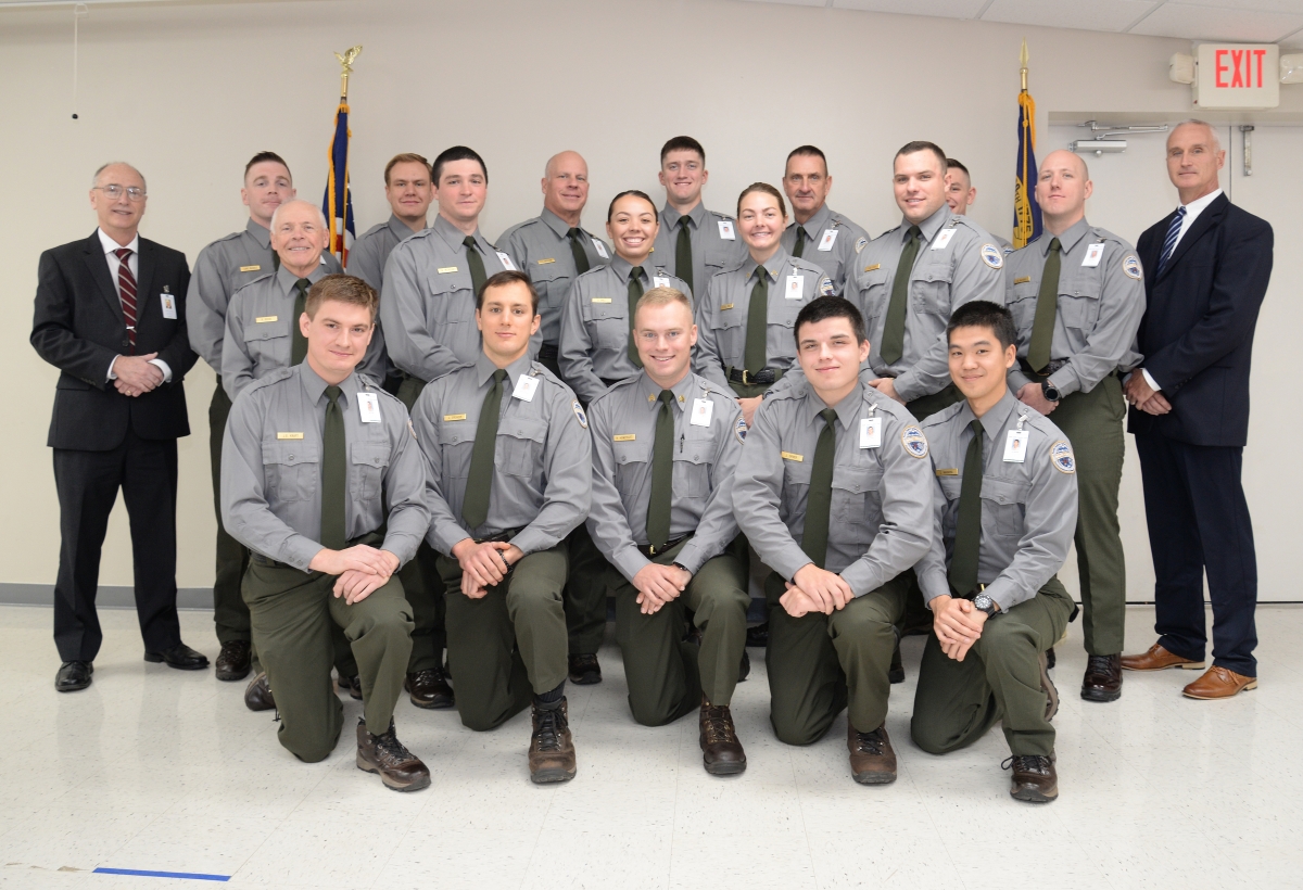 A group of recent law enforcement graduates huddle together for a group picture.