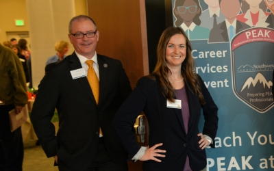 Man and woman stand in front of a vertical Career Services banner.