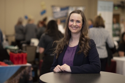 Woman stands in foreground of busy job fair