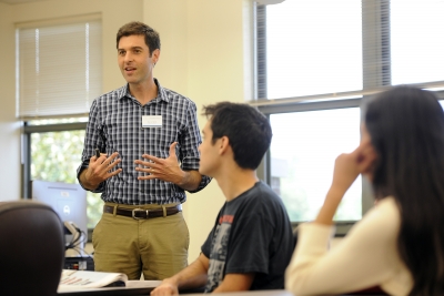 Man speaks in front of classroom; several students listen in foreground