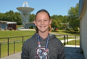 A young girl smiles outside of a science camp