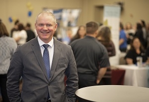 A man in a suit smiles in a crowd of people