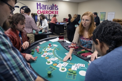 Woman deals cards on one of many casino-style tables at indoor training facility