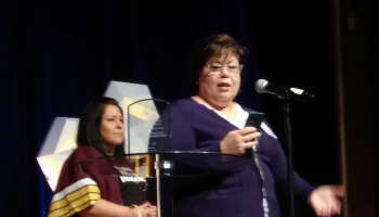 Woman standing to accept an award with another woman behind her.