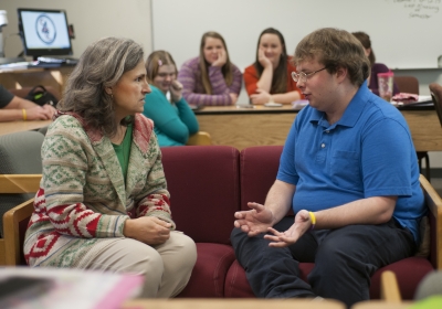 Female instructor and young man sitting on couch and having a serious discussion
