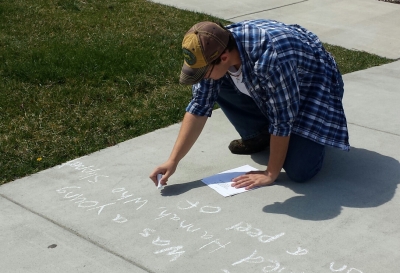 Male student writes a poem in sidewalk chalk on SCC's Jackson Campus.