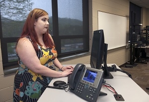 A woman wears a headset while typing on a computer