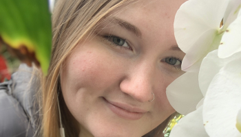 Young blonde female smiling among some flowers