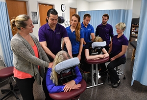 Instructor demonstrating therapeutic massage to a group of students.