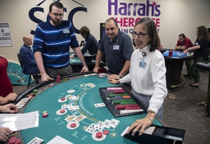 A woman is being trained on a table game for a casino.