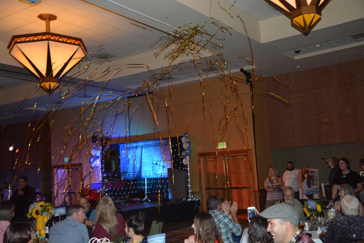 Gold Streamers fly through the air in a ballroom.