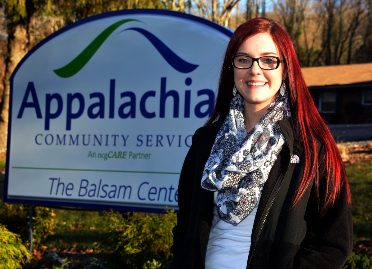 Lady stands outdoors in front of a "Balsam Center" sign