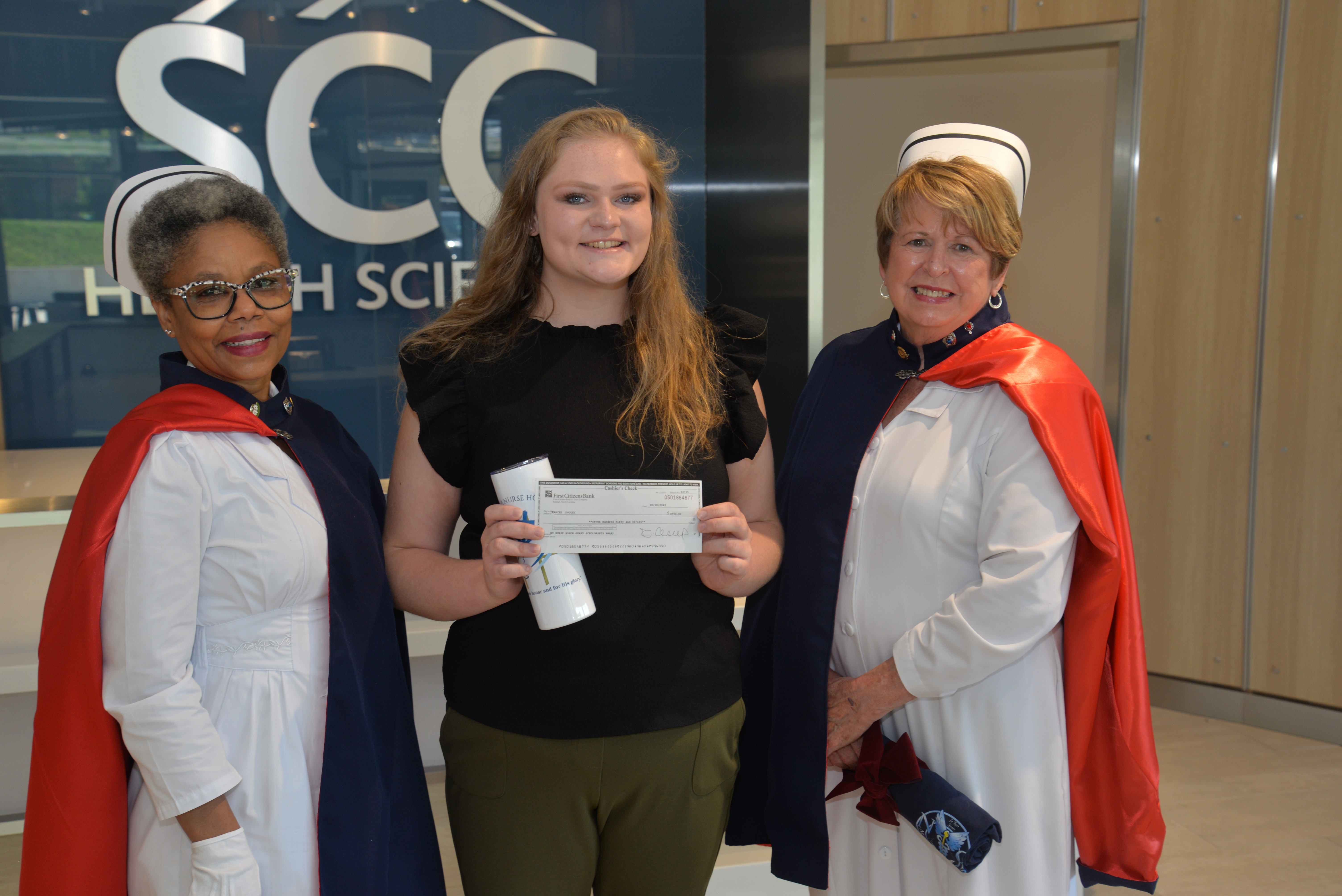 SCC student stands between two ladies wearing nursing uniforms
