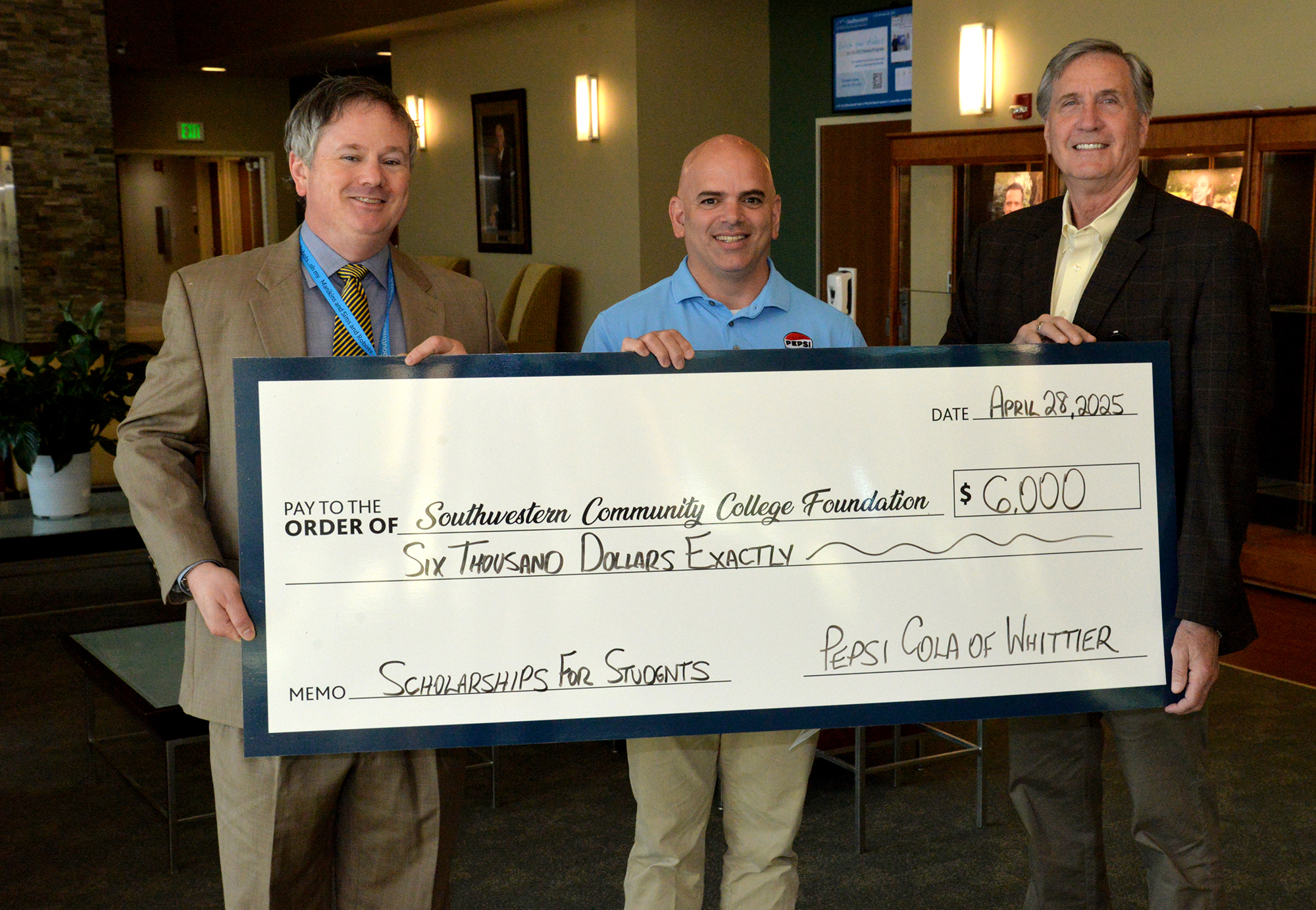 three men hold up large check