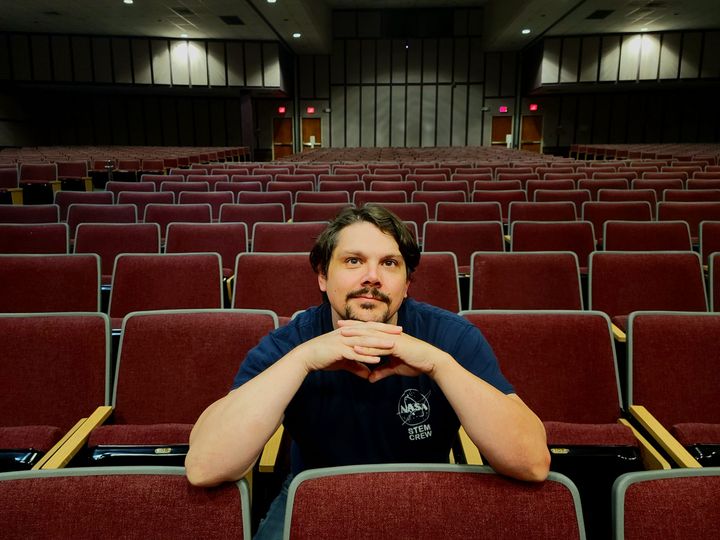 Matt Cass seated in vacant auditorium