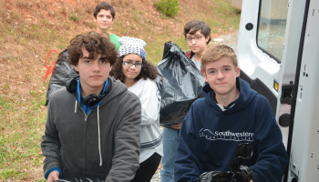 Five students load large bags filled with donations into a van.