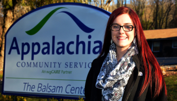 Lady stands outdoors in front of a &quot;Balsam Center&quot; sign