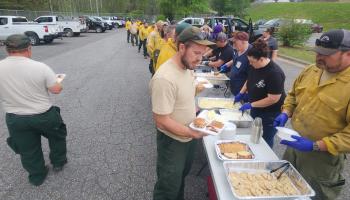 Southwestern Community College employees and area residents serve a meal to firefighters and emergency personnel on Monday, April 21, at Swain West Elementary School.
