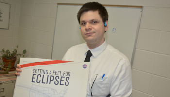 Man holds up a book cover entitled &quot;Getting A Feel For Eclipses&quot;