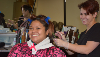 A female student trims on a female client's hair inside SCC's Cosmetology lab