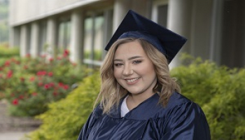 Young woman smiling in a graduation cap and gown