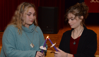 Student lights a fellow inductees candle during the ceremony.