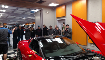 Students surround a red sports car at Passion Performance