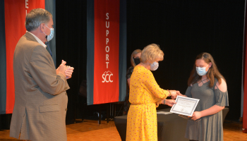 Woman hands a certificate to a student