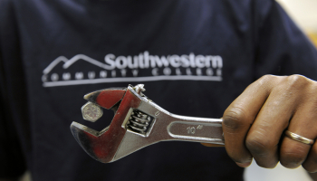 A man holds a magnetic wrench that has a bolt clinging to the top.