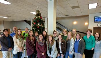 Group of people stand in front of Christmas tree