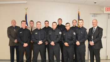 A group of law enforcement graduates huddle together for a group picture with their instructors.