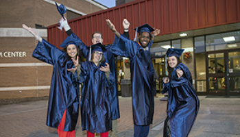 A group of graduates strike fun poses in their caps and gowns.