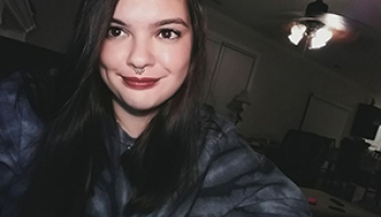 Young woman with dark hair and red lipstick smiles for a selfie