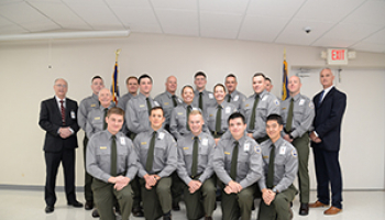 A group of recent law enforcement graduates huddle inside for a group picture.