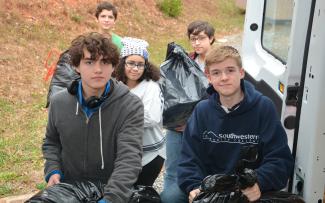 Five students load large bags filled with donations into a van.