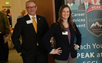 Man and woman stand at welcome table during a recent Job Fair.