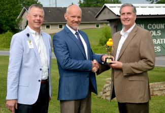 Three men pose outdoors for a photo.