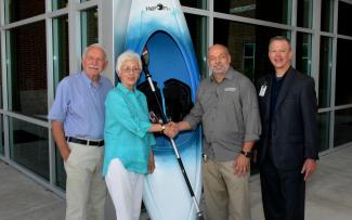 Three men and a woman stand beside a kayak outside a building on SCC's Jackson Campus in Sylva.