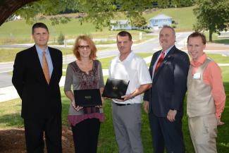 Students stand with SCC and SECU officials under a tree.