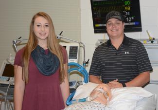 woman and man stand behind practice doll