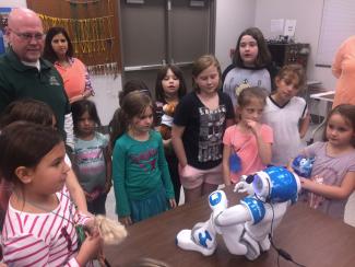 Group of people look at robot