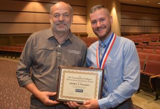 Student holding framed certificate poses with his instructor