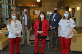Two nursing students stand beside administrators and an instructor