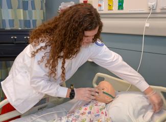 Nursing student works with a simulation mannequin