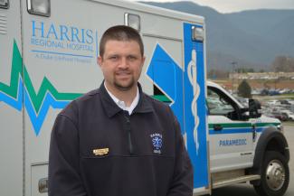 Man stands in front of an ambulance.